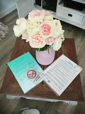 a table with a vase of flowers and some papers at La perle des Alpilles Résidence les MYRTILLES in Eyguières