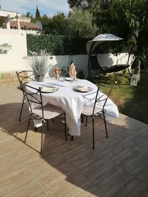 a table with a white tablecloth and chairs on a patio at La perle des Alpilles Résidence les MYRTILLES in Eyguières