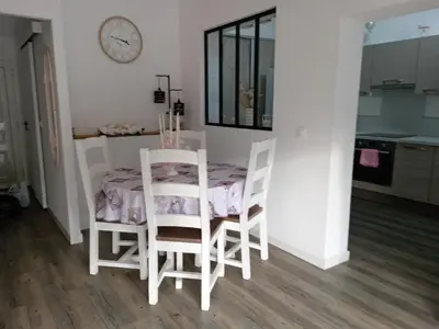 a table and chairs in a kitchen with a clock on the wall at La perle des Alpilles Résidence les MYRTILLES in Eyguières