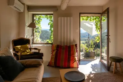 a living room with a couch and a sliding glass door at Les Maisons Mado in Venasque