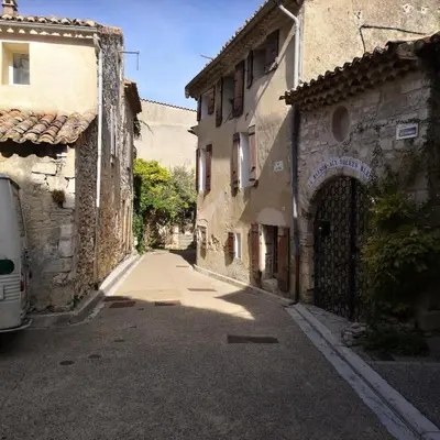 an alley with buildings and a van parked on the street at Les Maisons Mado in Venasque