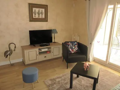 a living room with a tv and a chair at Chez Marielle in LʼIsle-sur-la-Sorgue