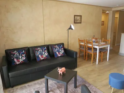 a living room with a black couch and a table at Chez Marielle in LʼIsle-sur-la-Sorgue