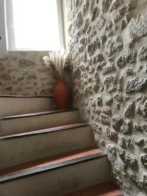 a vase sitting on the stairs next to a stone wall at L'Ensoleillée in Ménerbes