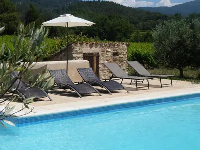 a group of chairs and an umbrella next to a swimming pool at Appartement St Victor in Puyvert