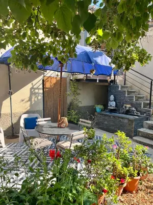 a patio with a table and a blue umbrella at Appartement St Victor in Puyvert