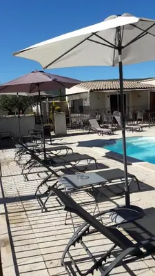 a group of chairs and umbrellas next to a pool at DANSAVAN Chambres d Hôtes Gite in Oppède