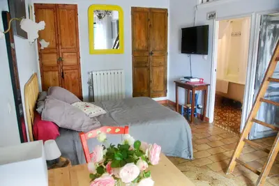 a bedroom with a bed and a table and a television at Les Volets Bleus Provence in Salon-de-Provence