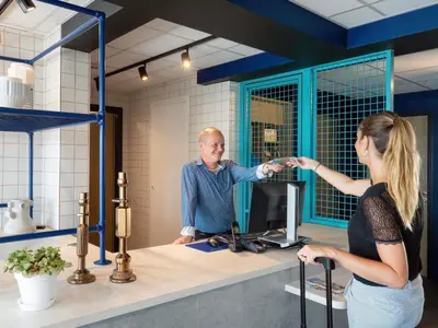 a bedroom with a white bed with a blue wall at ibis budget Pertuis Portes du Luberon in Pertuis