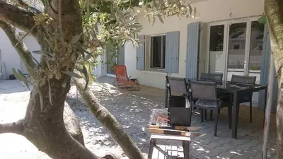 a patio with a table and chairs and a tree at Maison dans quartier calme in LʼIsle-sur-la-Sorgue