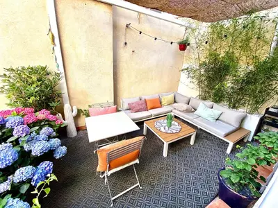 a patio with a couch and a table and flowers at Dar Saad Appartement terrasse climatisation centre d Aix in Aix-en-Provence