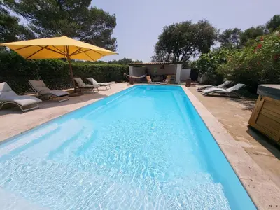 a blue swimming pool with an umbrella and chairs at Le Phoenix de Sainte Victoire in Saint-Marc-Jaumegarde