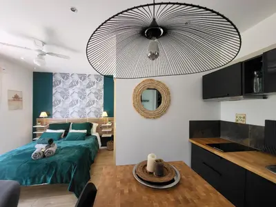a bedroom with a green bed and a kitchen at Le Phoenix de Sainte Victoire in Saint-Marc-Jaumegarde