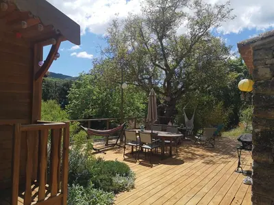 a deck with a table and chairs and an umbrella at Roulotte la clé du Luberon in Buoux