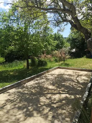 an empty patio under a tree in a field at Roulotte la clé du Luberon in Buoux
