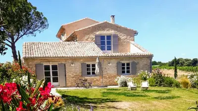 a stone house with two chairs in a yard at Le Cottage du Chat Blanc in Saint-Didier