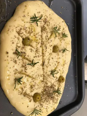 a pan with a pizza with cheese and green olives at Maison Lou Roucas in Cabrières-dʼAigues