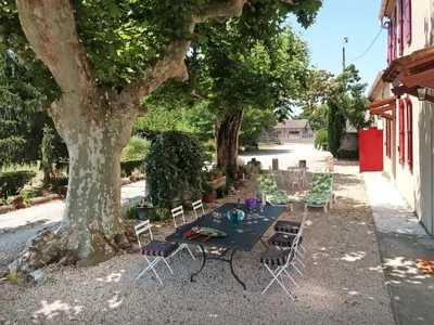 a table and chairs under a tree next to a building at Holiday Home Mas de la Gourmette by Interhome in Châteaurenard