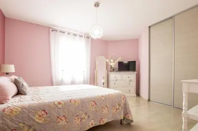 a bedroom with pink walls and a bed and a dresser at Villa Mireillo in Noves