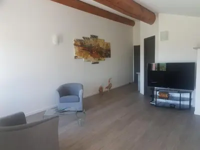 a living room with a flat screen tv and a chair at Mas Des Fugueyrolles in Cavaillon