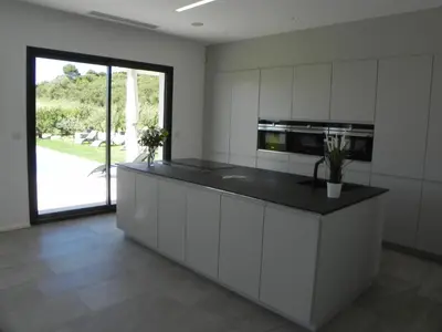 a kitchen with white cabinets and a black counter top at Là Mésange de Venasque in Venasque