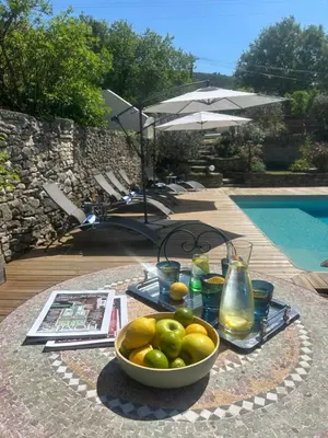 a bowl of fruit on a table next to a pool at Le mas jasmins in Ménerbes
