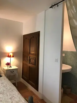 a bedroom with a bed and a sink and a wooden door at Le mas jasmins in Ménerbes