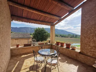 a patio with a table and chairs on a balcony at Mas Côté Cour in Maubec