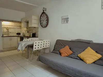 a living room with a couch and a clock on the wall at Charmant appartement avec clim - centre historique in Aix-en-Provence