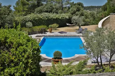 a large blue swimming pool in a garden at Quintessence Provence in Goult
