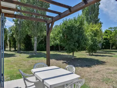 a white table and chairs under a wooden pergola at Residence Sun Hols Les Rives du Lac in Saint-Saturnin-lès-Avignon