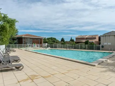 a large swimming pool with chairs and a fence at Residence Sun Hols Les Rives du Lac in Saint-Saturnin-lès-Avignon