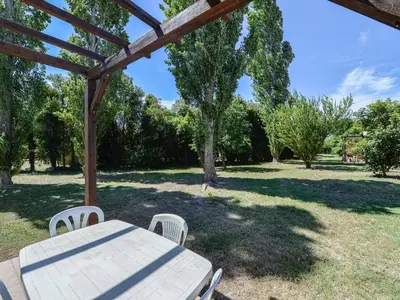 a picnic table and chairs under a wooden pergola at Residence Sun Hols Les Rives du Lac in Saint-Saturnin-lès-Avignon