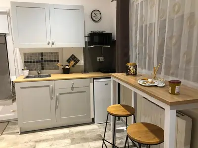 a kitchen with white cabinets and a counter and stools at Esprit Zen en Provence Studio Spa privatif in Cheval-Blanc