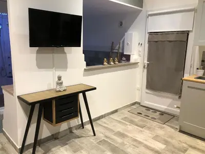 a room with a table and a television on a wall at Esprit Zen en Provence Studio Spa privatif in Cheval-Blanc