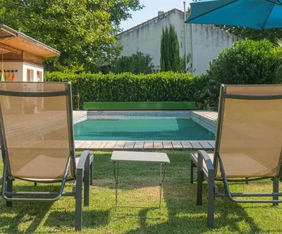 two chairs and an umbrella next to a swimming pool at Lodge St Exupéry in Le Thor