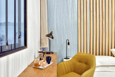 a bedroom with a yellow chair and a bed and a table at Les Nids de la Diane - Appart'Conforts in Pertuis