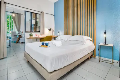 a bedroom with a large white bed with a desk and a room at Les Nids de la Diane - Appart'Conforts in Pertuis