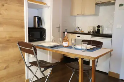 a kitchen with a table with two chairs and a bottle of wine at Floridianes by HRI in Aix-en-Provence