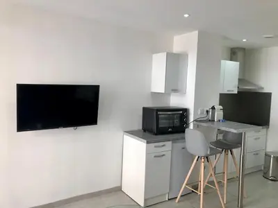 a kitchen with a microwave and a tv on the wall at Provençal Studio Netflix Appart-hotel-Provence in La Fare-les-Oliviers