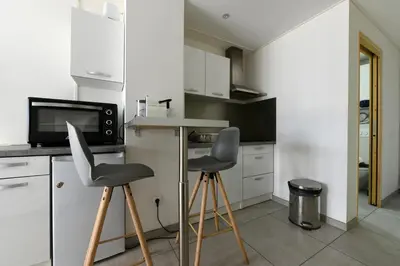 a kitchen with two bar stools and a microwave at Provençal Studio Netflix Appart-hotel-Provence in La Fare-les-Oliviers