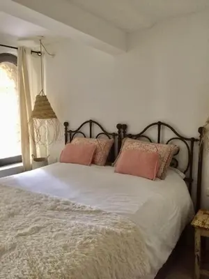 a bedroom with a bed with two pillows and a window at La petite maison in Lourmarin
