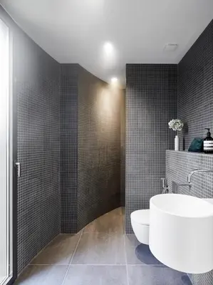 a bathroom with a white tub and black tiles at Hôtel le Jas de Joucas in Joucas