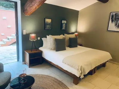 a bedroom with a large white bed with green walls at Hôtel le Jas de Joucas in Joucas