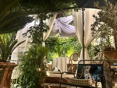 a patio with a table and a white canopy at la villageoise, chambre troglodyte pitoresque au cœur du village in Rognes