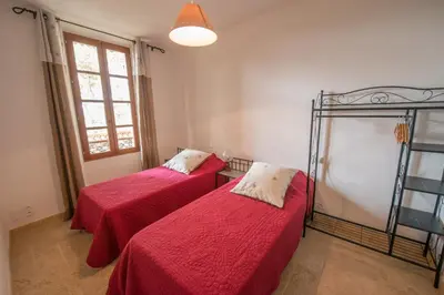 two beds in a room with red sheets at La Treille et L'Impasse in Ansouis
