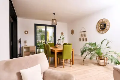 a living room with a table and green chairs at La Velleronnaise in Velleron