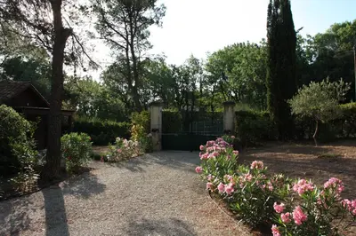 a garden with a gate and some flowers and trees at Logis au milieu des pins in Le Puy-Sainte-Réparade