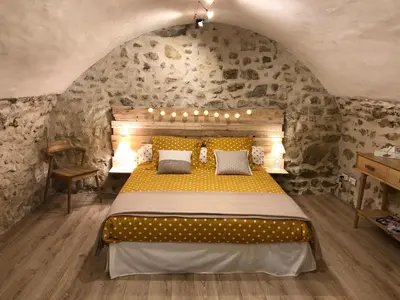 a bedroom with a large bed in a stone wall at L'Atelier de Marie in Eyguières
