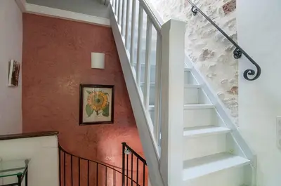 a staircase in a home with an orange wall at La Marisol in LʼIsle-sur-la-Sorgue